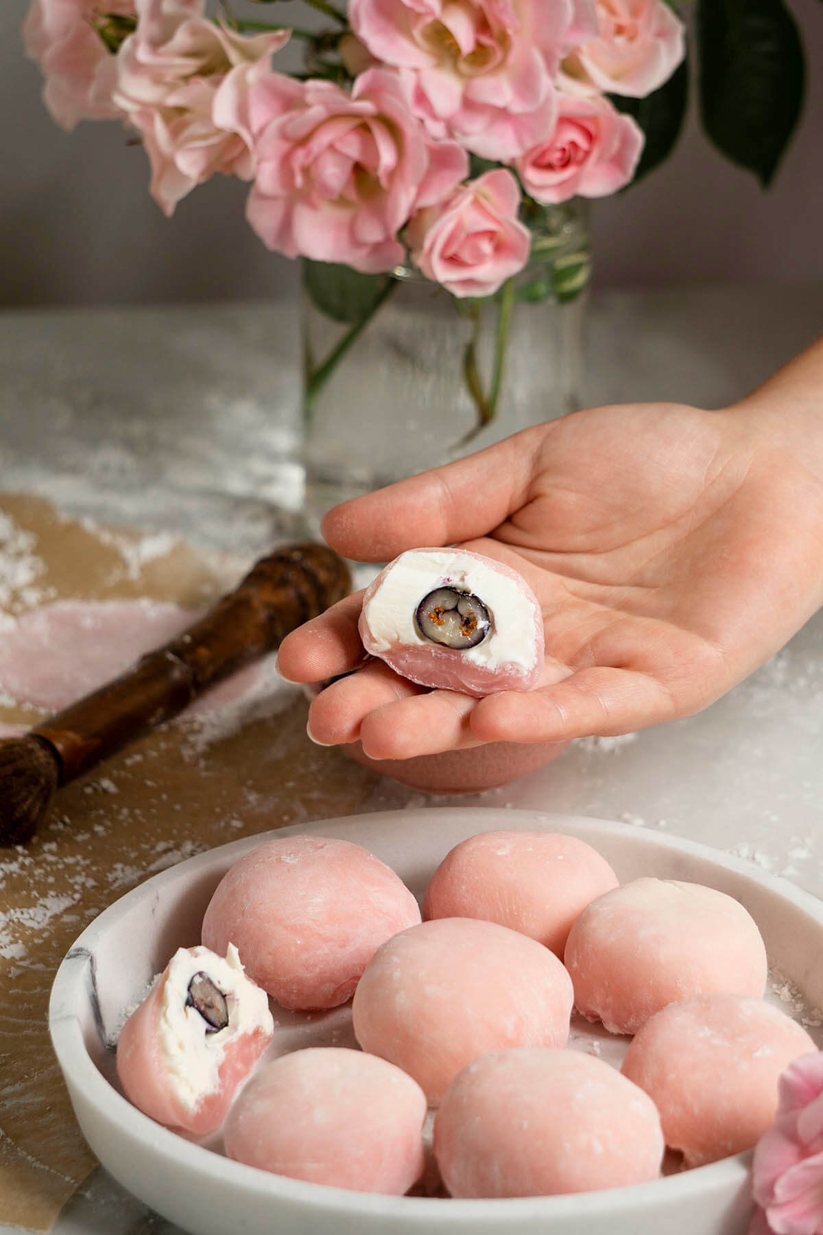 Процесс приготовления моти. Моти в разрезе в женской руке на фоне кухонного стола.